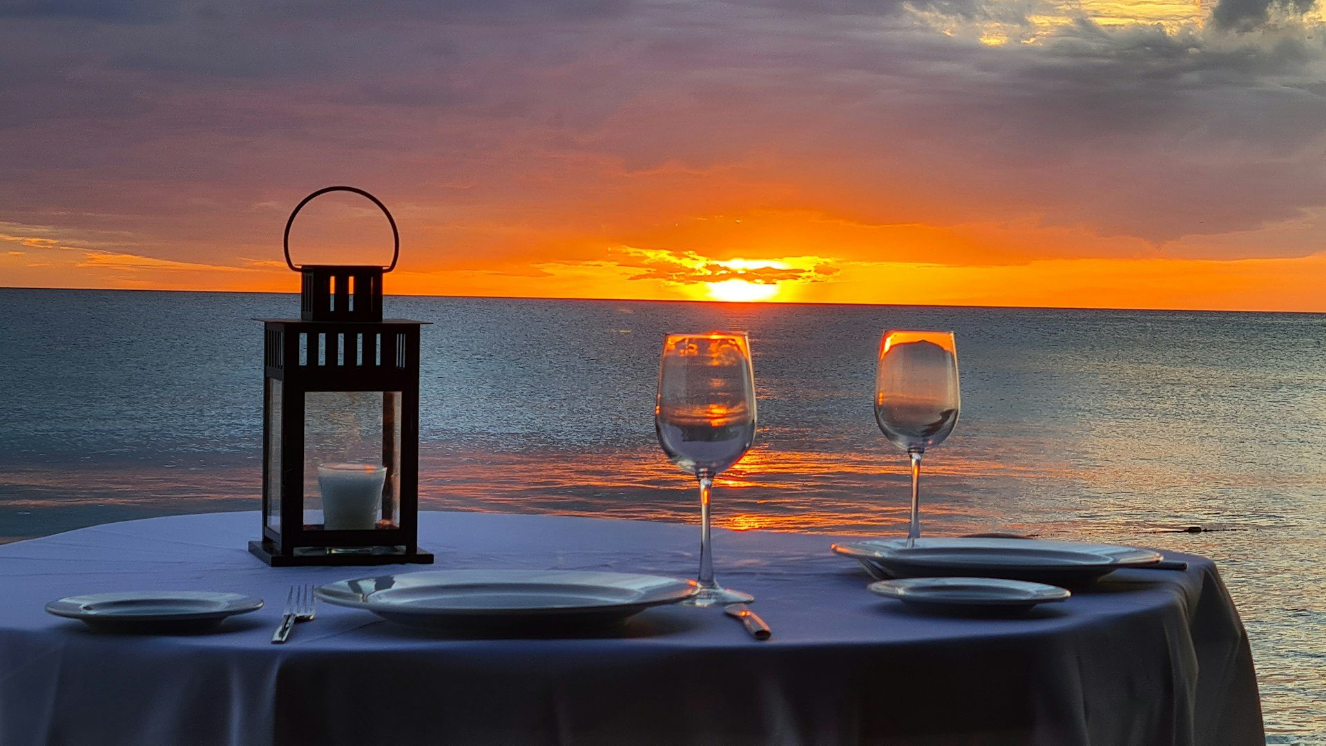 A table set for dinner on the sand at dusk