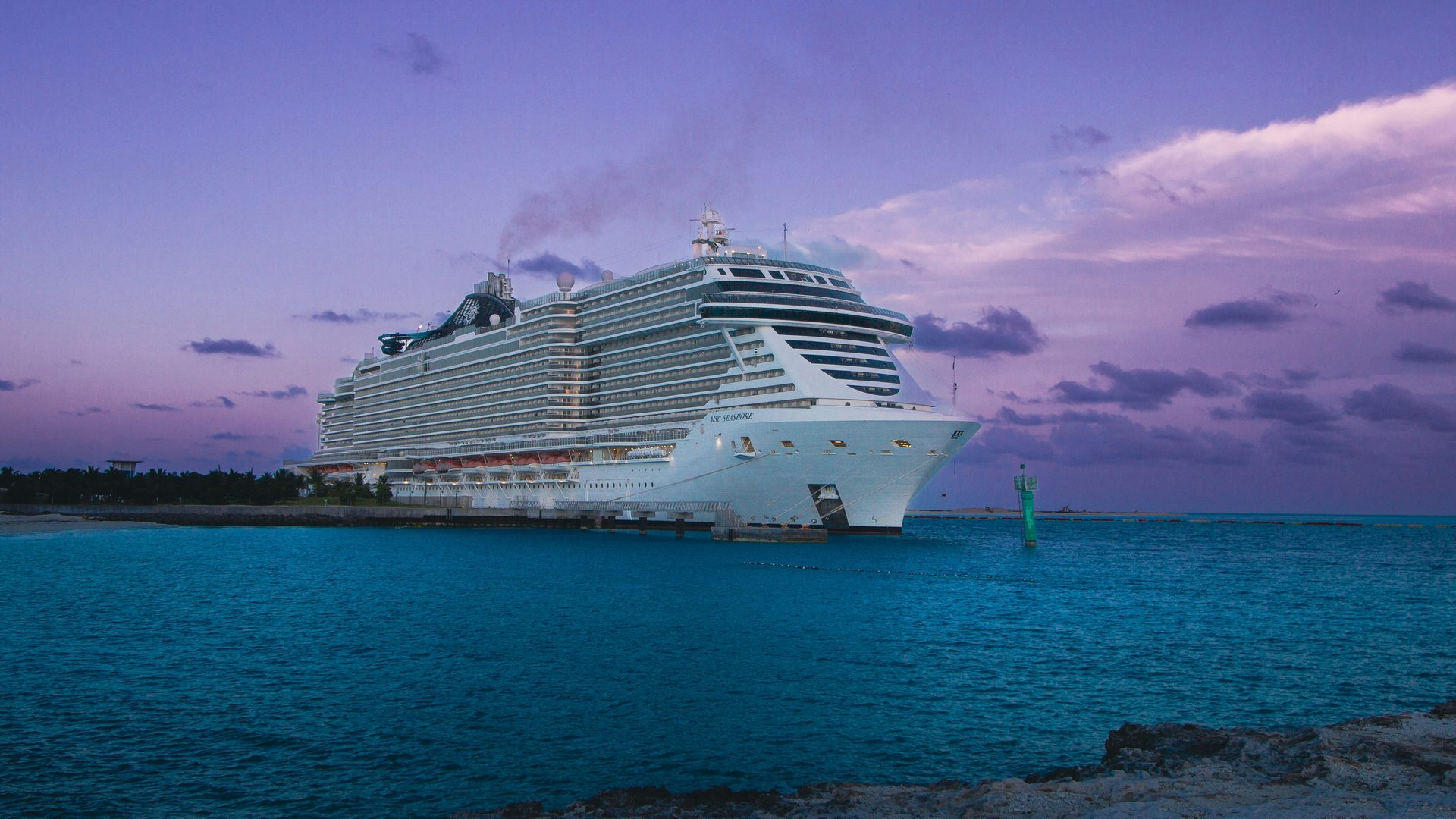 A ship docked at dusk beneath a pink sky