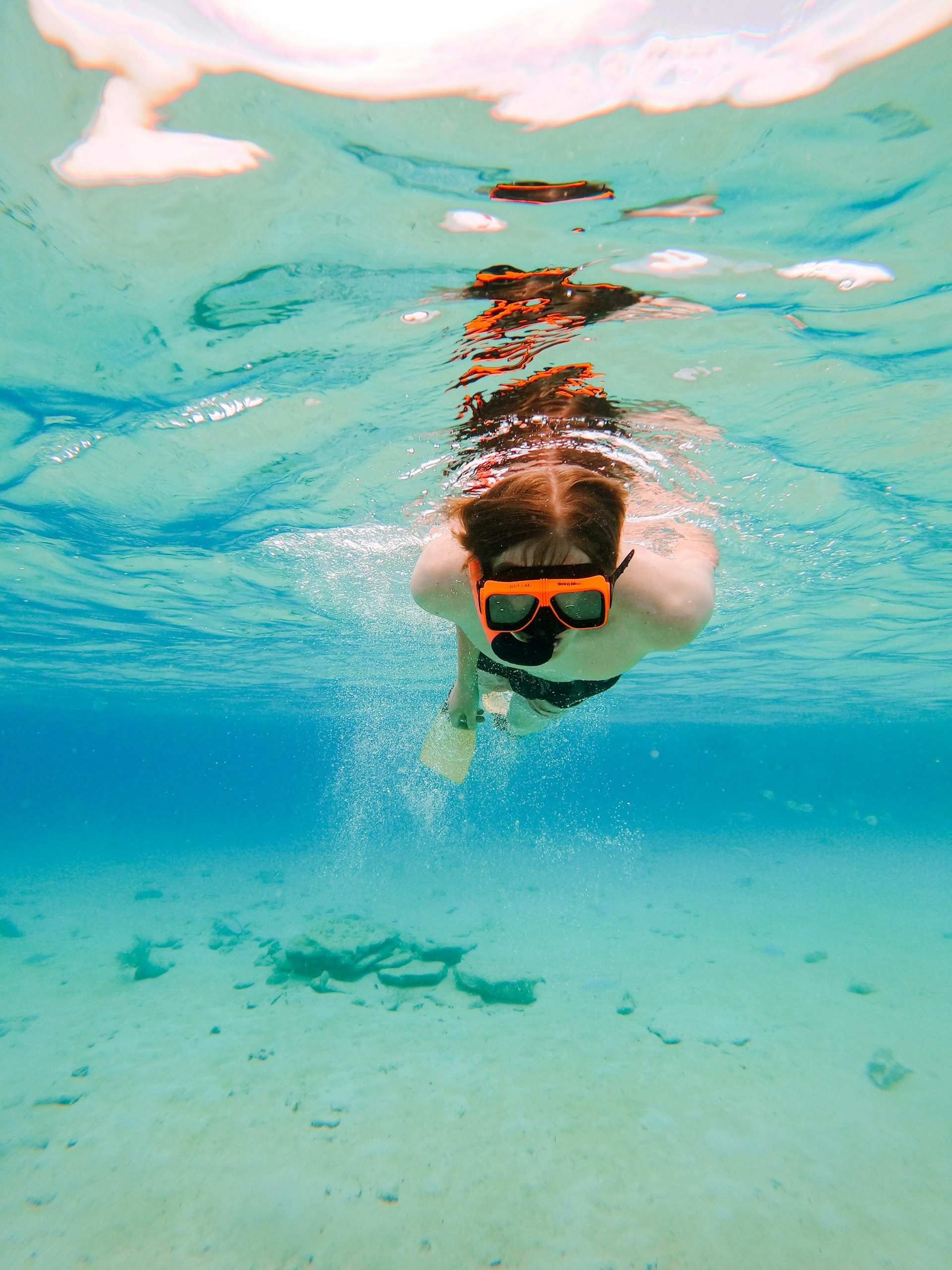 A child snorkelling in shallow turquoise water